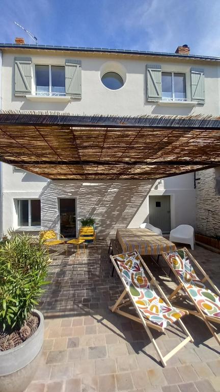 a patio with two deck chairs and a house at La Demoiselle in Les Ponts-de-Cé