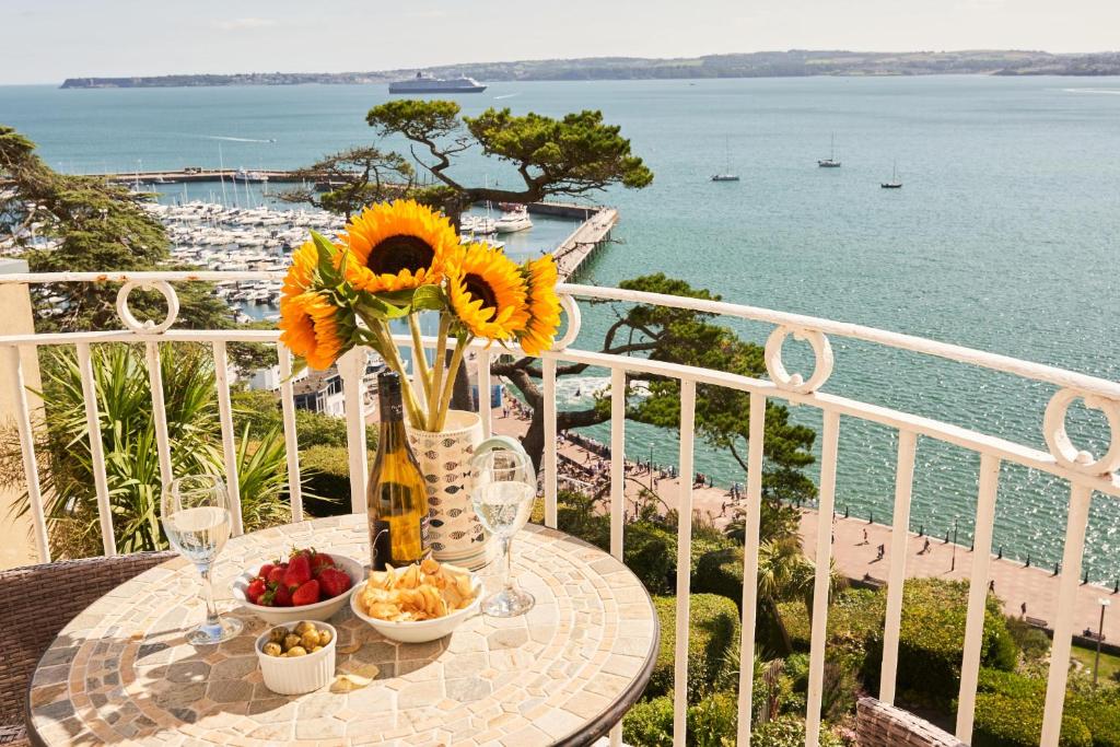 a table with a vase of sunflowers and fruit on a balcony at Bayfort Sea Studio - Comfortable Couples Retreat with Stunning Coastal Views in Torquay
