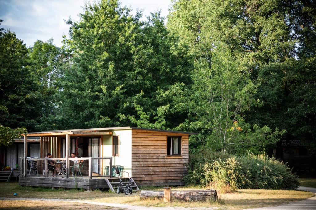 ein kleines Haus mit Leuten auf der Veranda in der Unterkunft Huttopia Les Châteaux in Bracieux