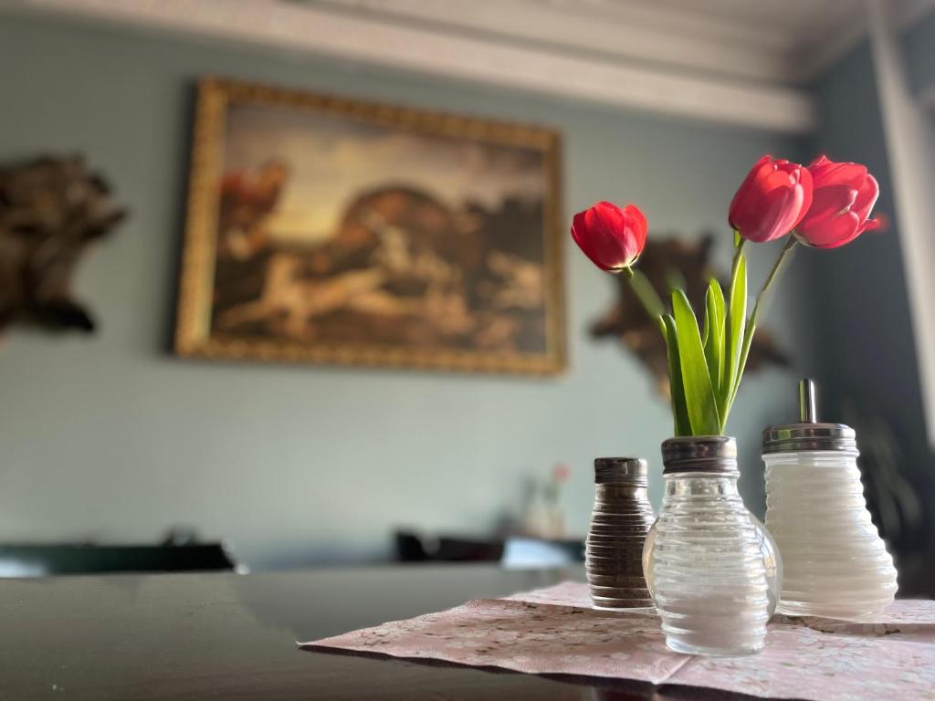 a table with three glass bottles with red tulips in them at Hotel Černý Orel Žatec in Žatec