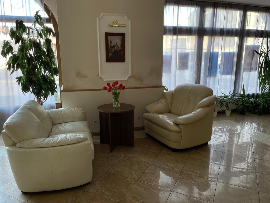 two chairs and a table in a room with windows at Hotel Černý Orel Žatec in Žatec