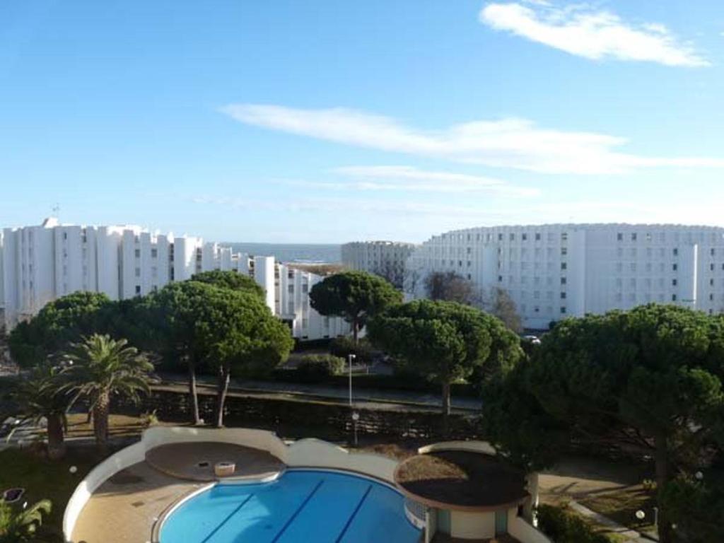 - une vue sur un bâtiment avec une piscine et des arbres dans l'établissement 2 pièces cabine à La Grande Motte avec piscine et garage - FR-1-328-170, à La Grande Motte