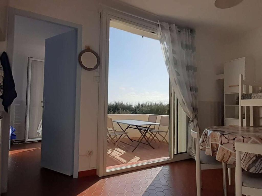 Cette chambre dispose d'une porte s'ouvrant sur une terrasse avec une table. dans l'établissement Appartement avec terrasse et parking, accès direct plage - FR-1-782-5, au Barcarès