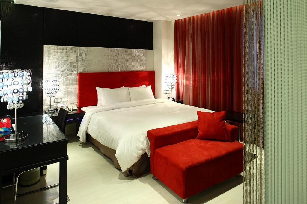 a bedroom with a large bed and a red chair at Hsiangkelira Hotel in Kaohsiung