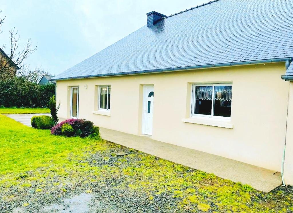 une maison blanche avec une porte et une cour dans l'établissement Grande et belle maison à 5 minutes de la mer, à Penvénan