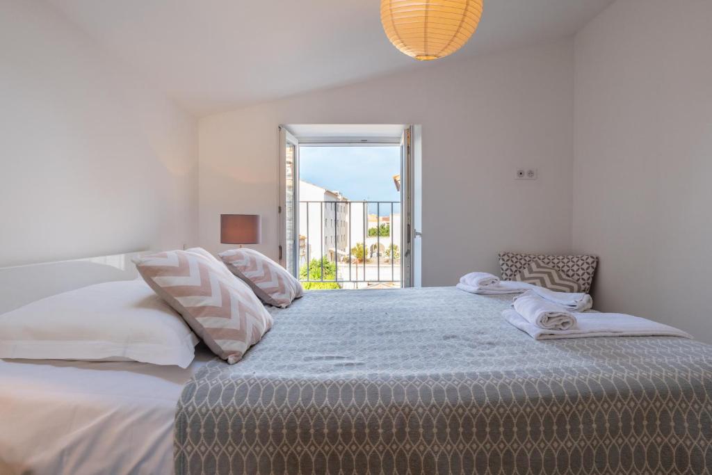 a white bedroom with a large bed with a window at Duplex en plein centre in Propriano