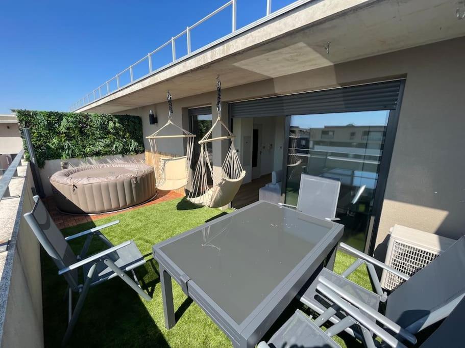 d'une terrasse avec une table, des chaises et un hamac. dans l'établissement Superbe studio avec Jacuzzi a Montpellier pres d arene, à Montpellier