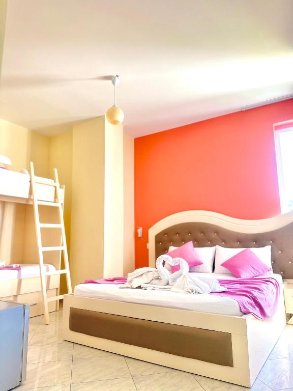 a bedroom with a bed with an orange wall at Hotel Garden in Vlorë