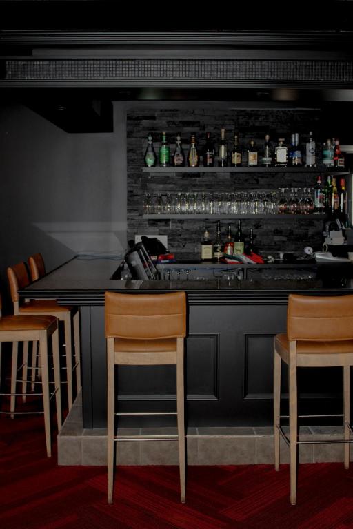 a bar with three chairs and a counter in a restaurant at Auberge le Parasol in Saguenay