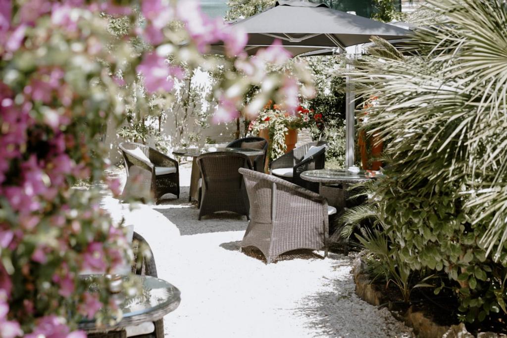 une terrasse avec des tables, des chaises et des fleurs roses dans l'établissement Ideal Sejour Cannes - Stylish Boutique Hotel with quiet garden, à Cannes