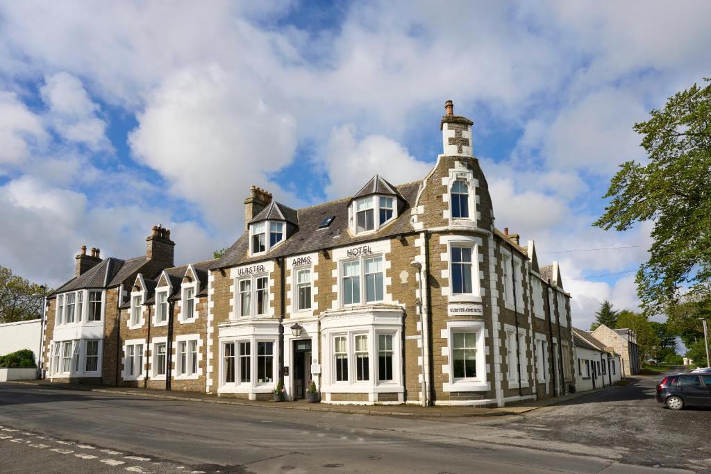 a large brick building with white windows on a street at Ulbster Arms Hotel near Thurso in Halkirk