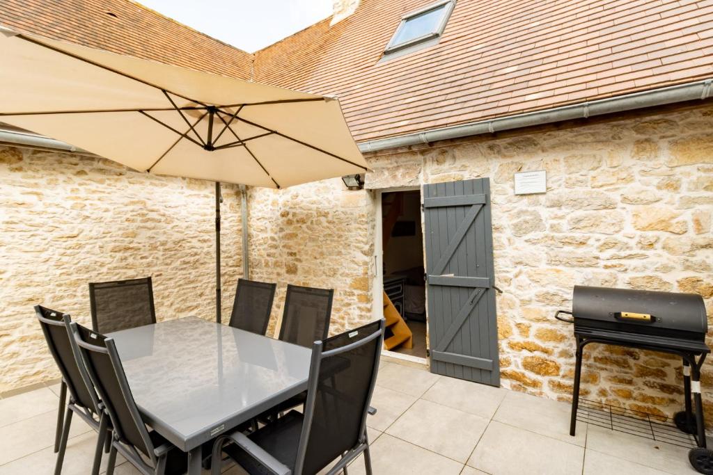 a patio with a table and an umbrella and a grill at La Boutique 2 à 4 personnes in Lacave