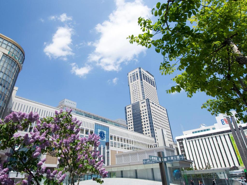 a city skyline with tall buildings and purple flowers at JR Tower Hotel Nikko Sapporo in Sapporo