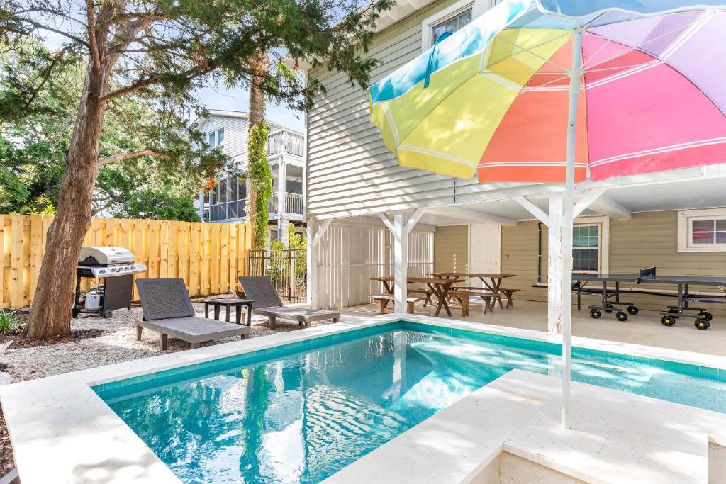 a swimming pool with an umbrella next to a house at Caretta Cottage in Tybee Island