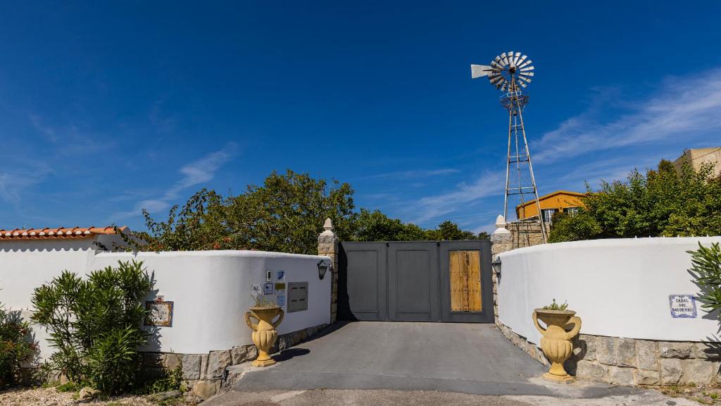 a gate to a driveway with a windmill in the background at Kochab Sintra by LovelyStay in Sintra