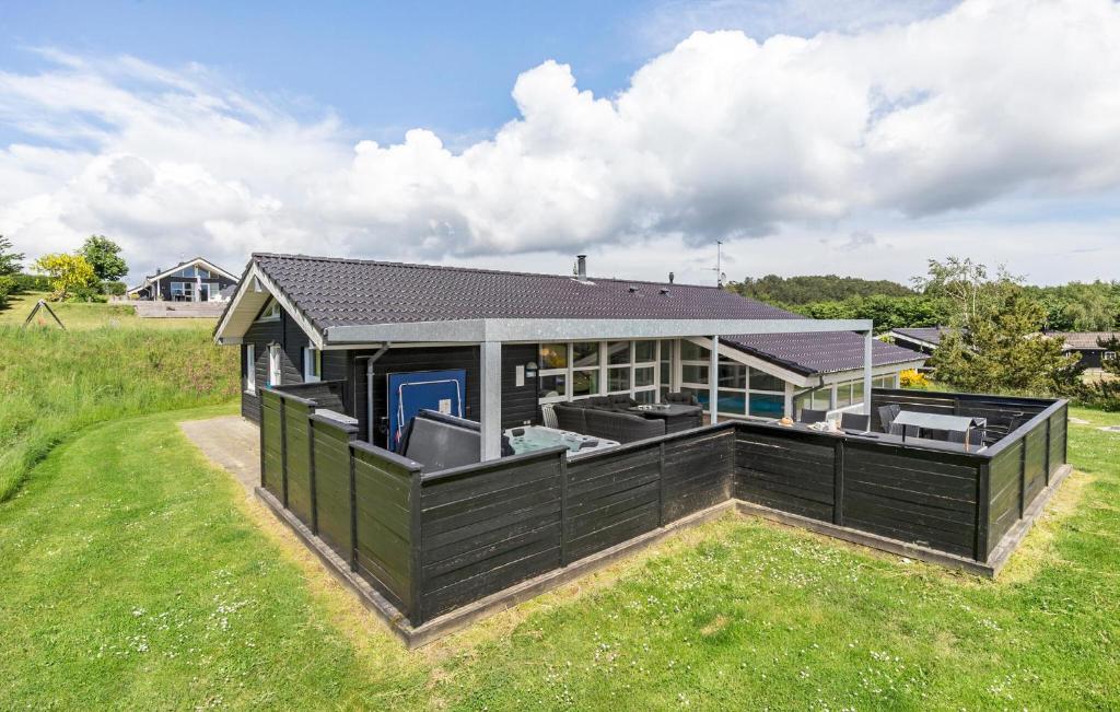 a house with a black fence in a field at Beautiful Home In Ebeltoft With Wifi in Ebeltoft