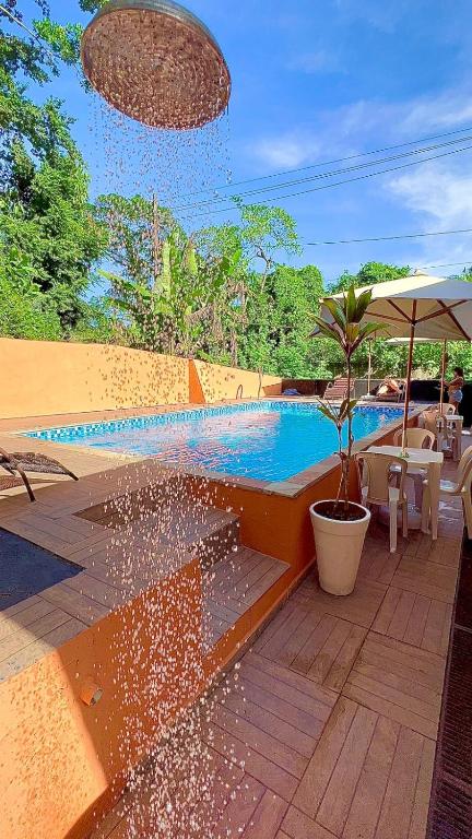 a swimming pool with a potted plant and an umbrella at Pousada Eco Beach in Ubatuba