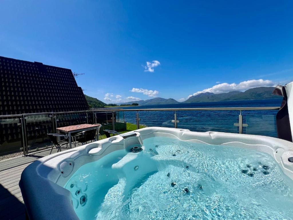 a jacuzzi tub with a view of the water at Loch Linnhe Waterfront Lodges with Hot Tubs in Glencoe