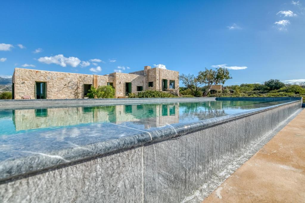 an infinity pool in front of a stone house at Villa Sand and Stone in Aliki