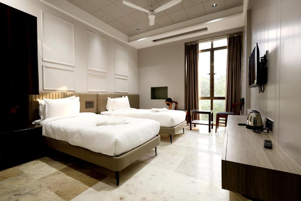a hotel room with two beds and a television at Hotel Statusinn, Ichalkaranji in Ichalkaranji