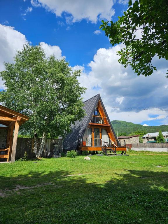 una casa con un tetto nero e un albero di B&B Cottage in Mestia a Mestia