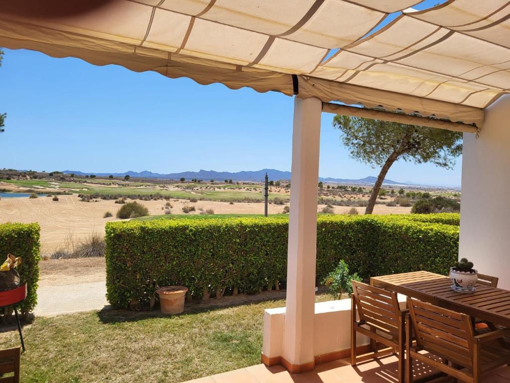 a patio with a table and a view of a field at Luxury Ground Floor Apartment at Golf Resort Condado de Alhama with Private Garden & Pools in El Romero