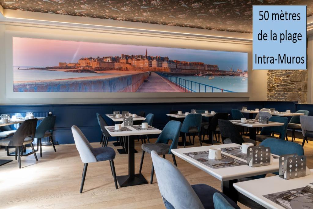 un ristorante con tavoli e sedie e un grande schermo di Hotel De L'univers a Saint Malo