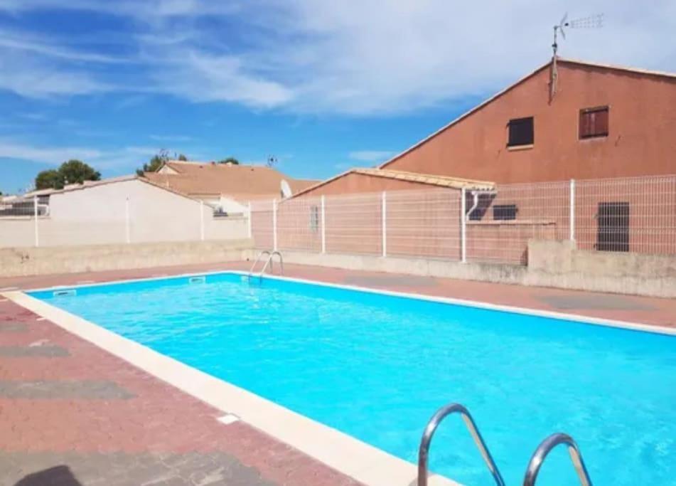 une grande piscine bleue à côté d'un immeuble dans l'établissement Agréable pavillon T3 Gruissan, à Gruissan