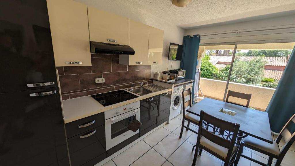 une cuisine avec une cuisinière et une table avec des chaises dans l'établissement Joli et coquet T2 - Caïcos 46, à Canet