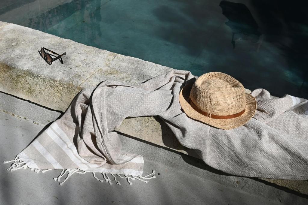 une personne portant un chapeau assise sur un rebord au bord de l'eau dans l'établissement Maison atypique proche Luberon et Avignon, à Châteauneuf-de-Gadagne
