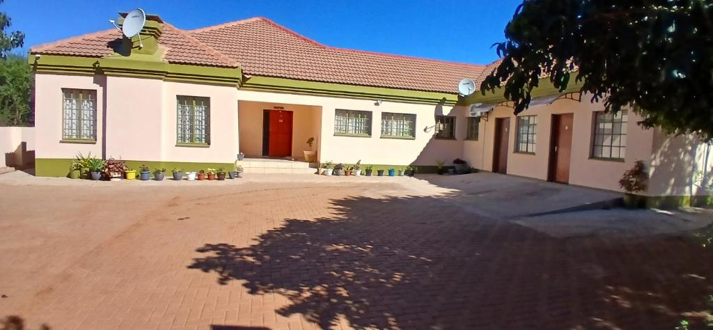 a house with a red roof and a driveway at Thokgamo Bed and Breakfast in Kanye