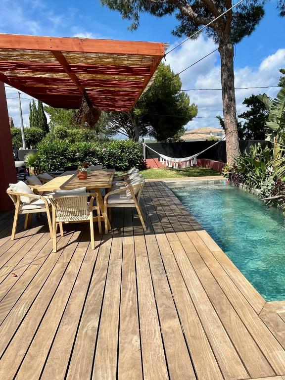 - une terrasse en bois avec une table et des chaises à côté de la piscine dans l'établissement Villa Uvéa, à Saint-Aygulf
