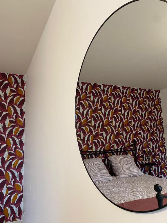 un miroir sur un mur à côté d'un lit dans l'établissement Le Studio de Marcy, à La Ferté-sous-Jouarre