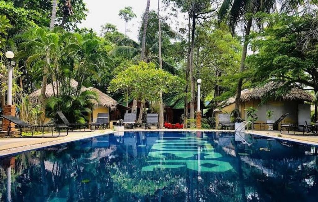 a large swimming pool in a resort with trees at Sunset Serenity Cove in Koh Phangan