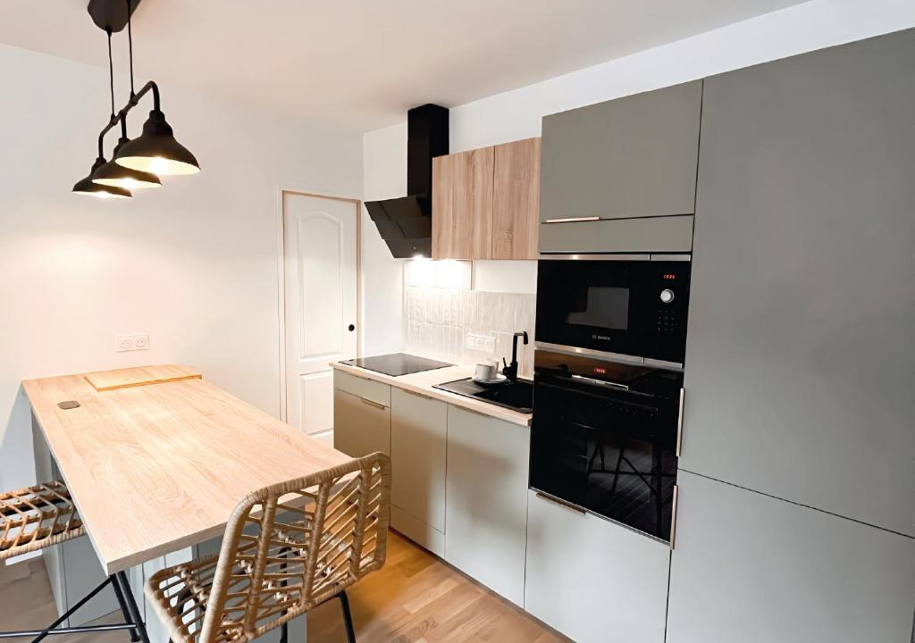 une cuisine avec des placards blancs et une table en bois dans l'établissement Appartement VANNES proche gare tout équipé, à Vannes