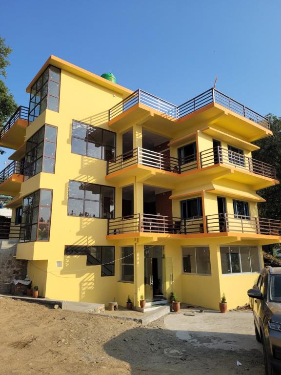 a yellow apartment building with a car parked in front at 11 Gaon Homestay Lansdowne in Lansdowne