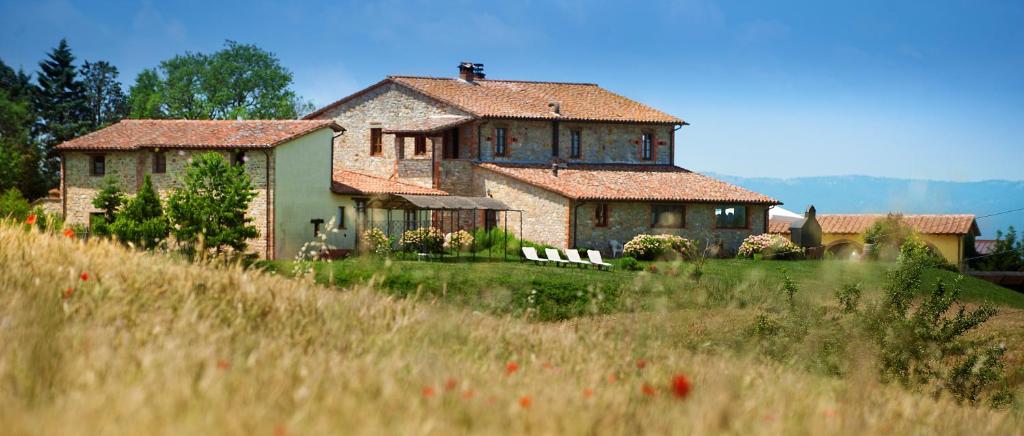 una casa grande en una colina con un campo delante en Agriturismo Gattogiallo, en Montegabbione