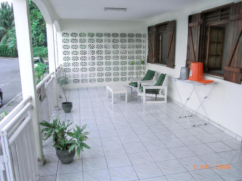 un portico con pavimento piastrellato bianco e sedie di Maison de 2 chambres avec vue sur la mer terrasse amenagee et wifi a Petit Bourg a 3 km de la plage a Petit-Bourg