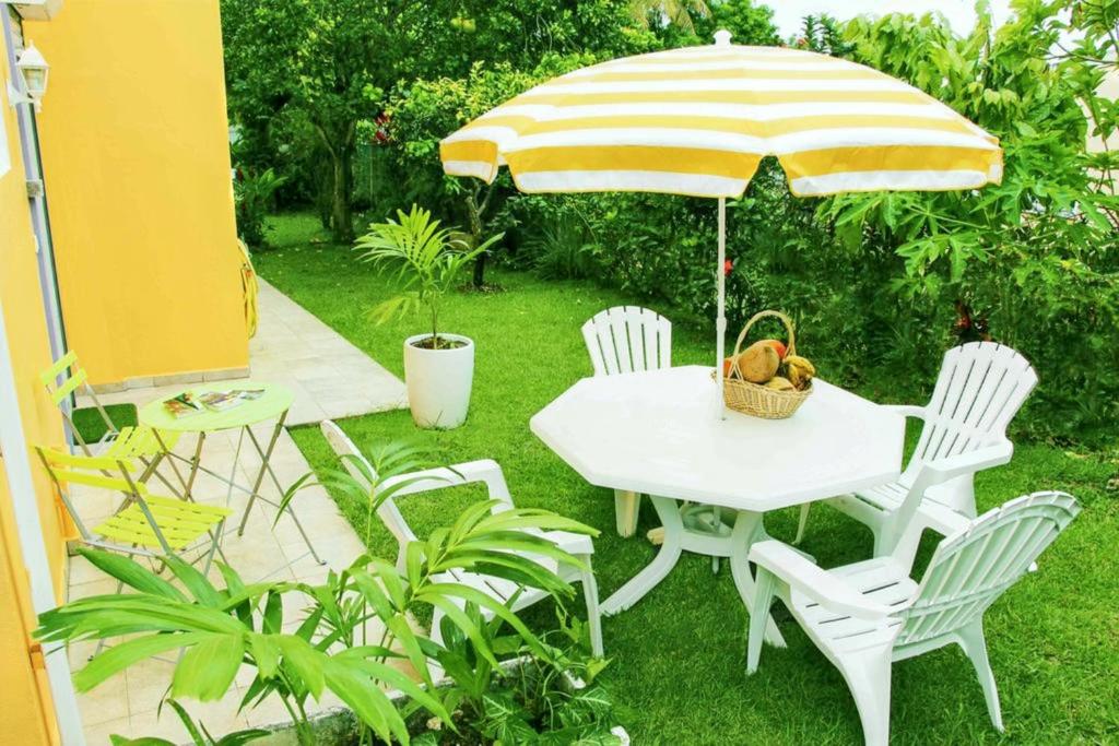 una mesa blanca y sillas con sombrilla en Appartement d'une chambre avec jardin amenage et wifi a Baie Mahault, en Baie-Mahault