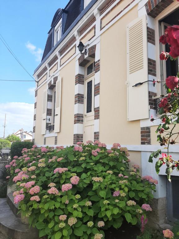 un bâtiment avec des fleurs roses devant lui dans l'établissement La p'tite bourgeoise Auxerroise, demeure de charme., à Auxerre