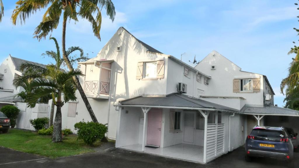 a white house with a car parked in front of it at 3 bedrooms house at Grand Baie 500 m away from the beach with private pool enclosed garden and wifi in Grand-Baie
