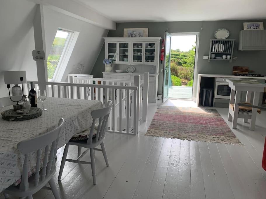 a white dining room with a table and a fireplace at Greenhills Cottage -Overlooking Slieve League in Kilcar