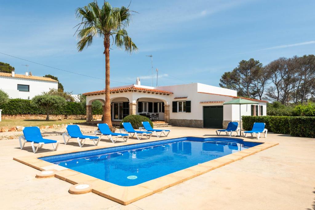 a swimming pool with chairs and a house at Villa Binisaret I by Mauter Villas in Cala Blanca