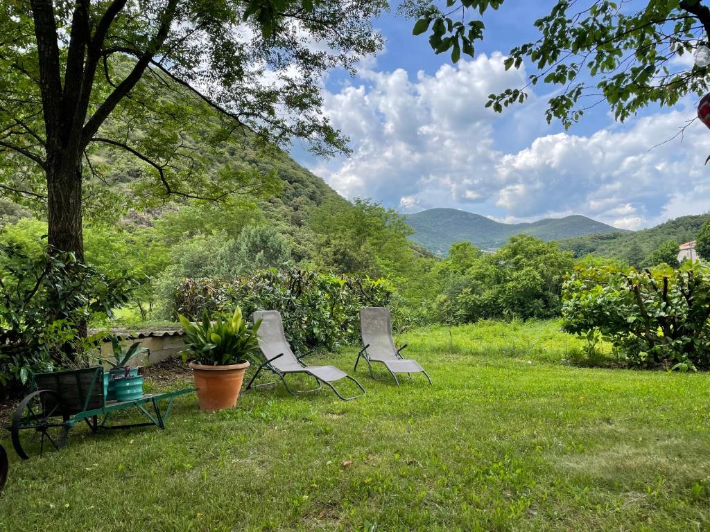 two chairs and a table in a yard with mountains at La Campagne in Saint-André-de-Majencoules