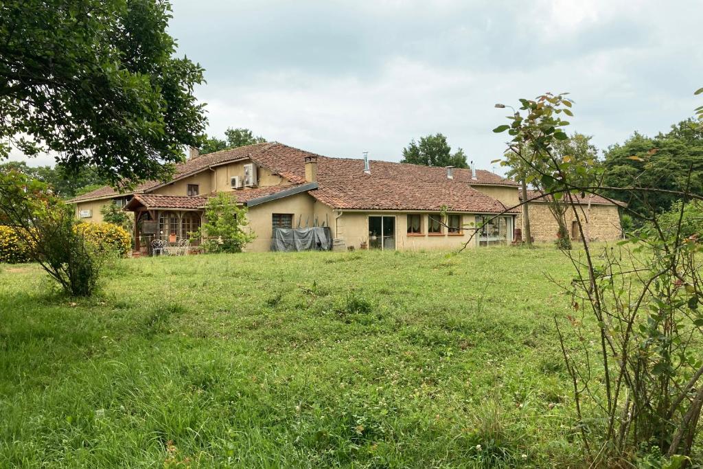 an old house with a grass field in front of it at Gîtes et Camping Hameau Nouste Temps in Castelnau-Magnoac
