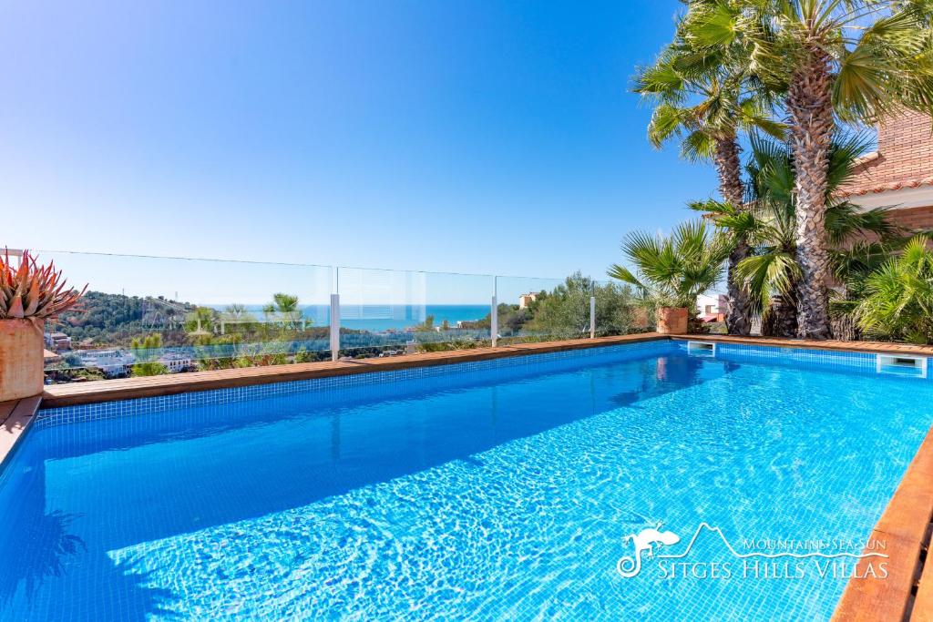 een groot blauw zwembad met palmbomen op de achtergrond bij Super Villa Oasis Fab Sea and Sitges View with Private Pool and Air Conditioning in Sitges