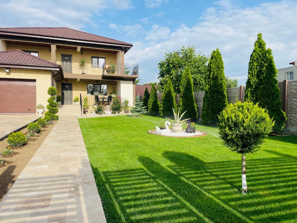 a house with a lawn with a fountain at Vila Bya in 2 Mai