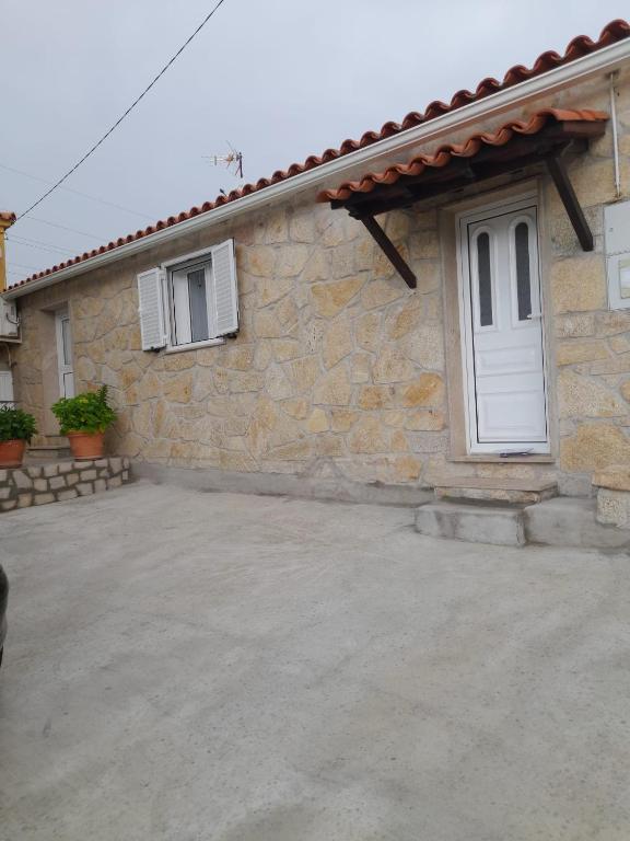 a stone house with a white door and a patio at O Cantinho da Auzenda in Torre de Moncorvo