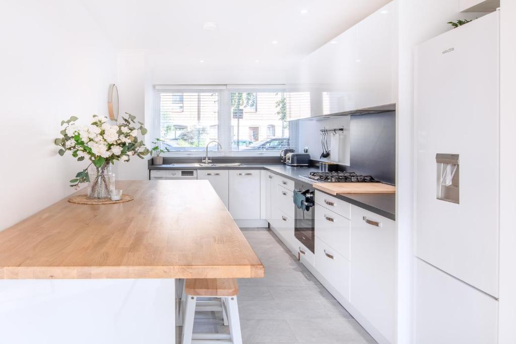 a kitchen with white cabinets and a wooden counter top at The Camden Retreat in London