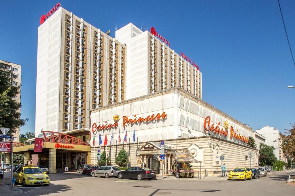 a large hotel building with cars parked in front of it at Ramada by Wyndham Sofia City Center in Sofia